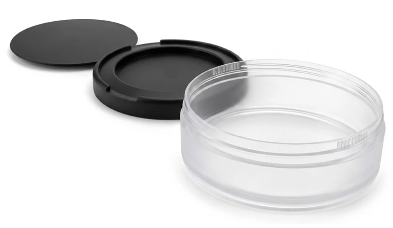 Clear plastic snus can with black screw-top lid disassembled on white background
